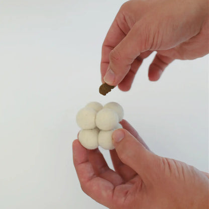 En hand som visar hur man kan kombinera den bubbliga ullbollen med aktivering för katten