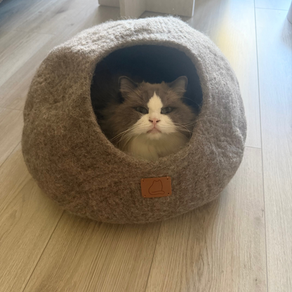 Ragdollkatt vilar ombonat i Haven kattgrotta i jordbrun, handgjord i naturlig ull.