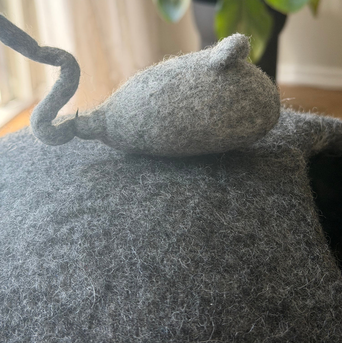 Närbild på en handgjord ullmus som dekoration på den stengrå kattgrottan i ull